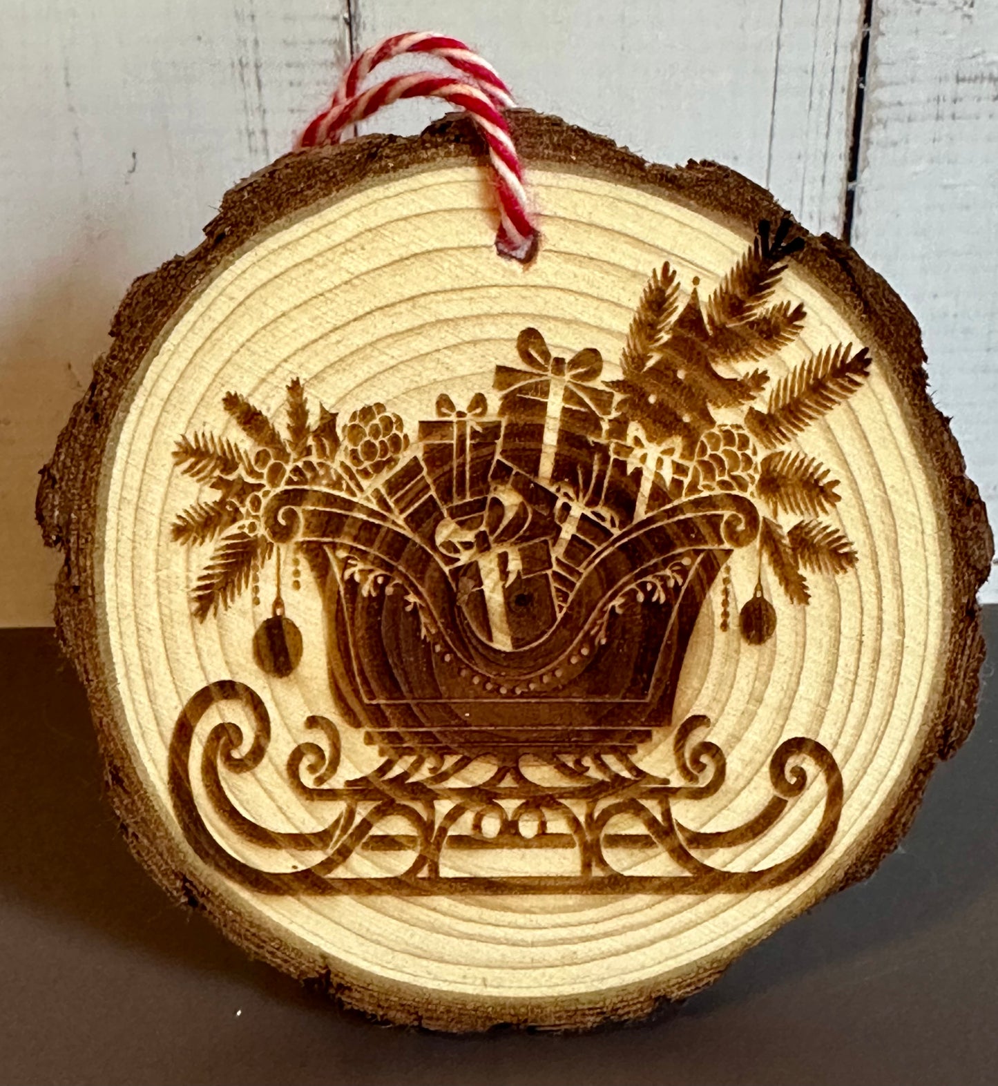 Engraved Live Edge Wooden Round Ornament - Presents and Pine in Sleigh